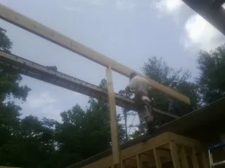Carpenter setting a ridge beam over a new addition frame — Ice Dam Removal by Roofing Brothers in Elwell