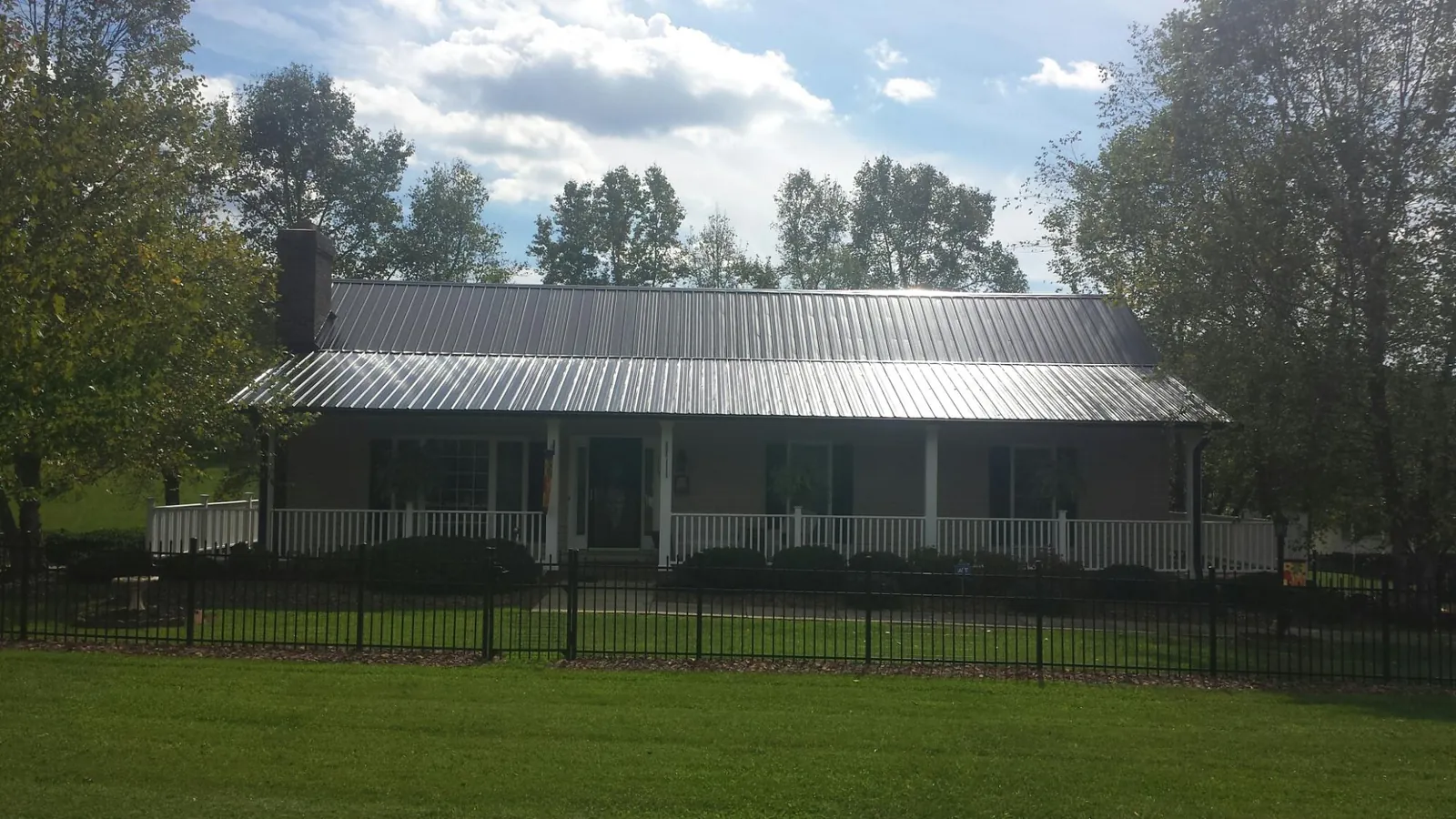 Gray metal roof on a brick ranch with a full width front porch — Gutter Guard Installation work by our crew in Elwell