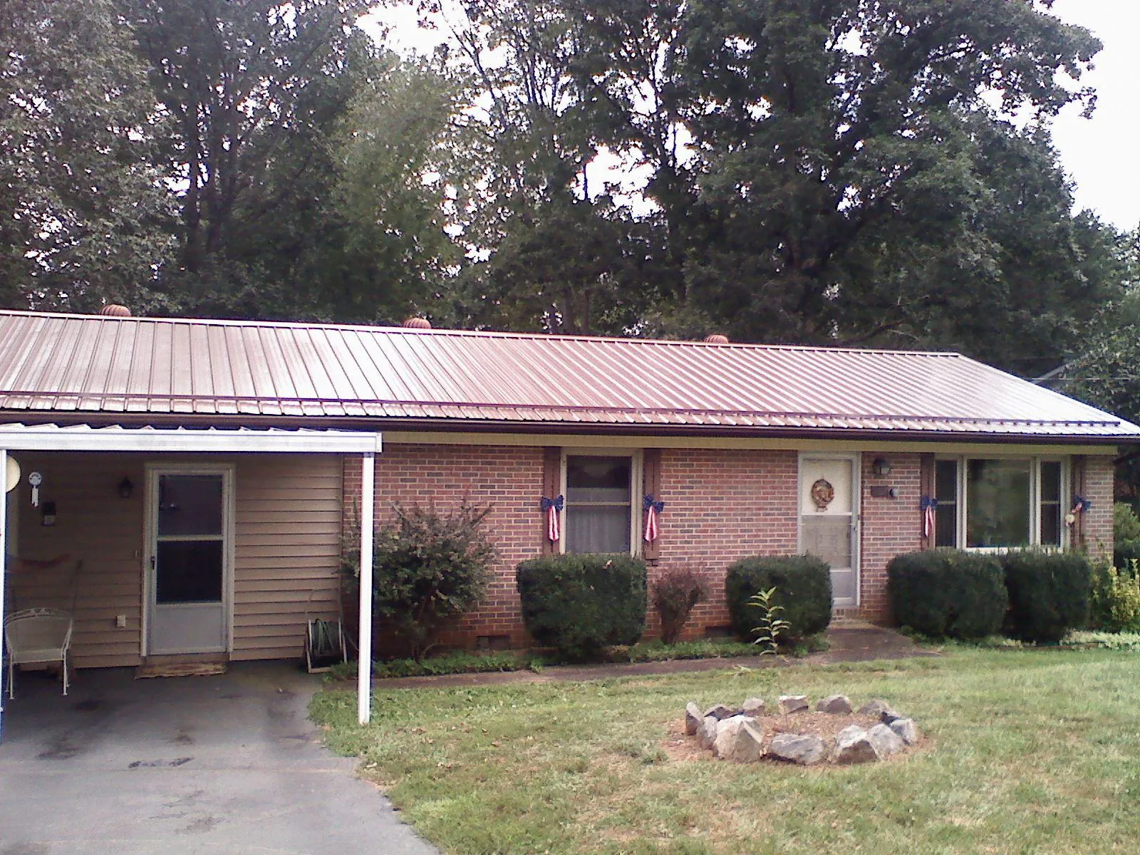 Bronze metal roof and carport on a brick ranch home — Roof Repair work by our crew in Elwell